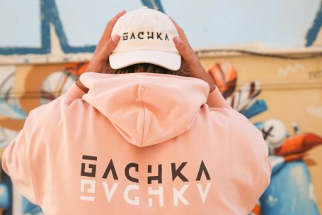 Person portant un sweat rose et une casquette blanche avec le logo "GACHKA".