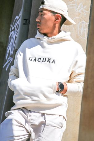 Jeune homme en sweat beige avec inscription «&nbsp;GACHKA&nbsp;», regardant sur le côté.